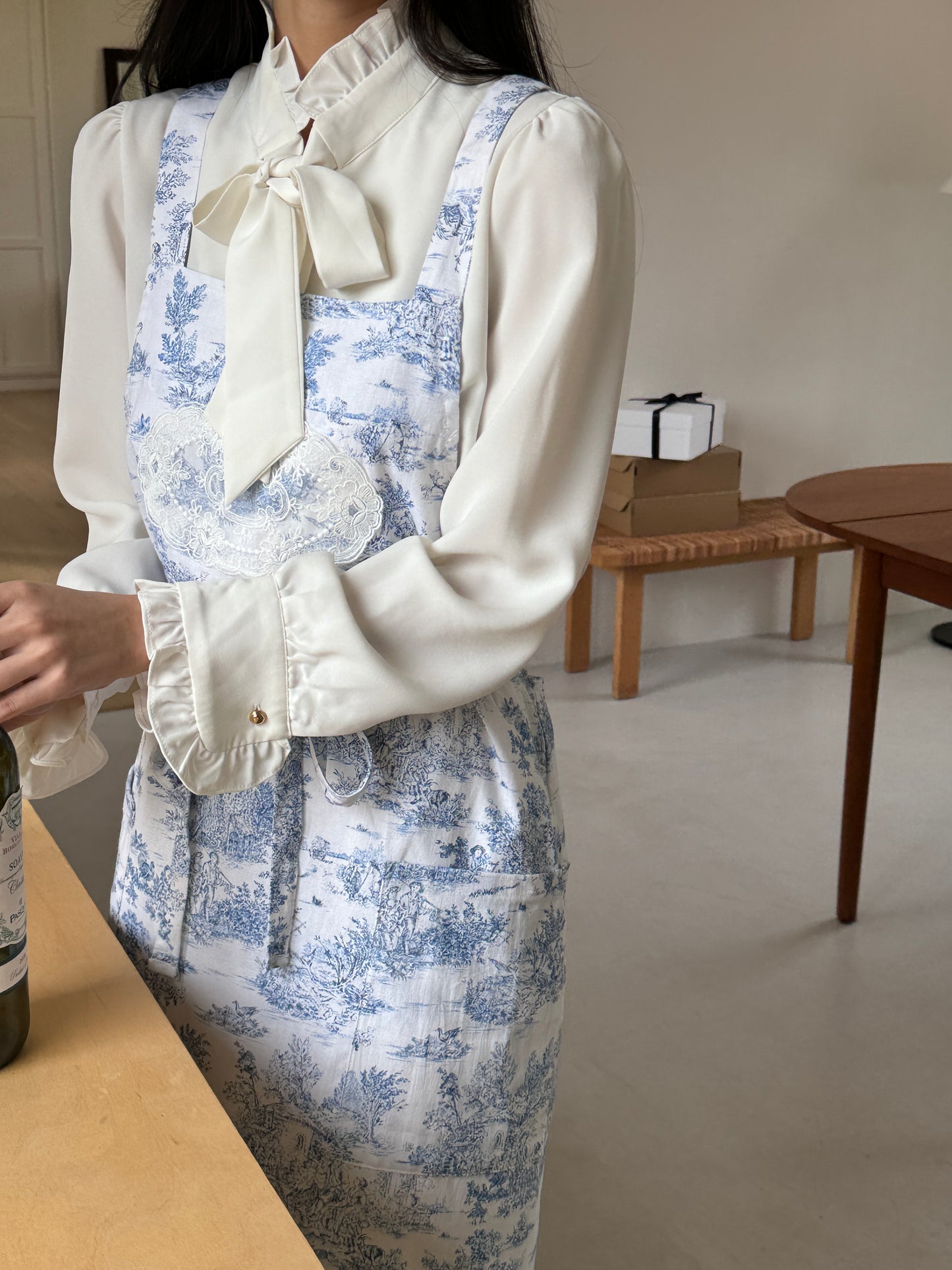 Model wearing Velouving Toile De Jouy Apron while preparing food in the kitchen.